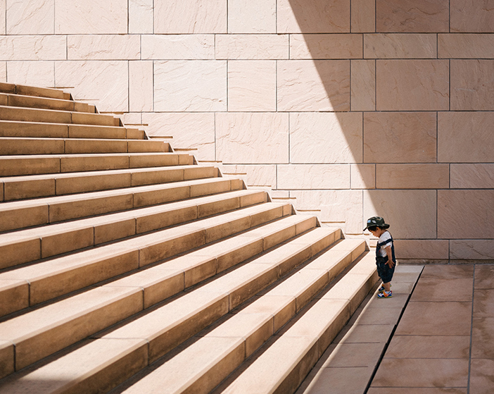 Kleines Kind steht vor der ersten Stufe einer lange Treppe